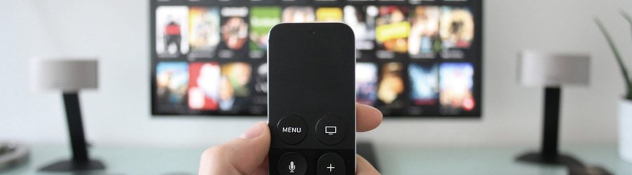 Person holding a remote in front of a TV screen with streaming options, showing how addressable TV works.
